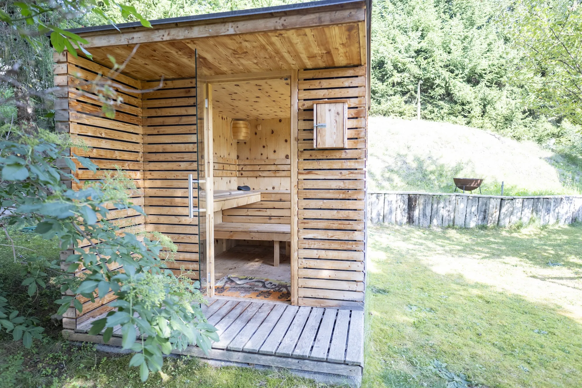Die private Gartensauna aus Holz, umgeben von Grün